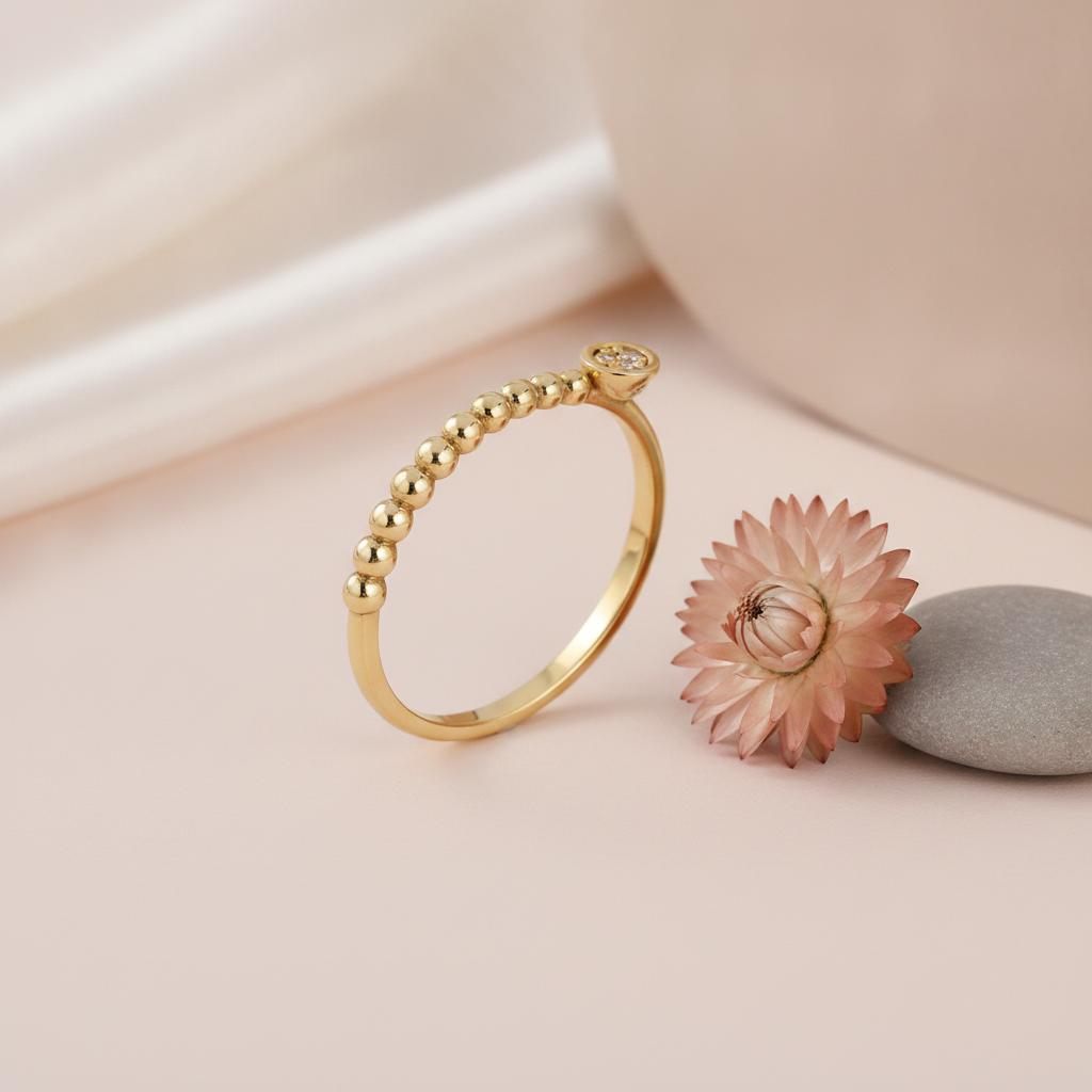 beaded gold ring with a round cluster of White CZ stones, styled with a dried flower and a pebble on a pink background