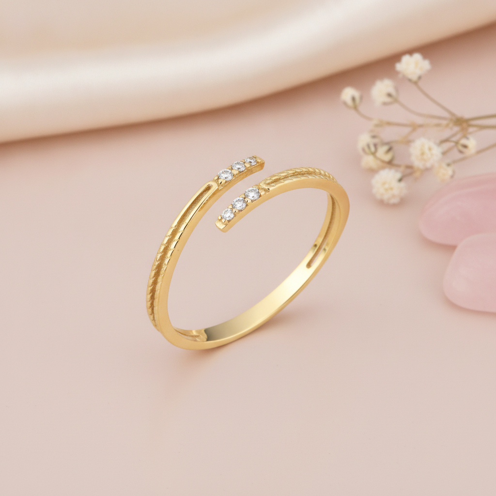 open wrap gold ring with textured and smooth bands finished with White CZ stones, styled with dried flowers on a pink background