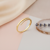 gold ring with an elevated row of White CZ stones on an asymmetrical band, styled with a dried lavender sprig on a two-tone background
