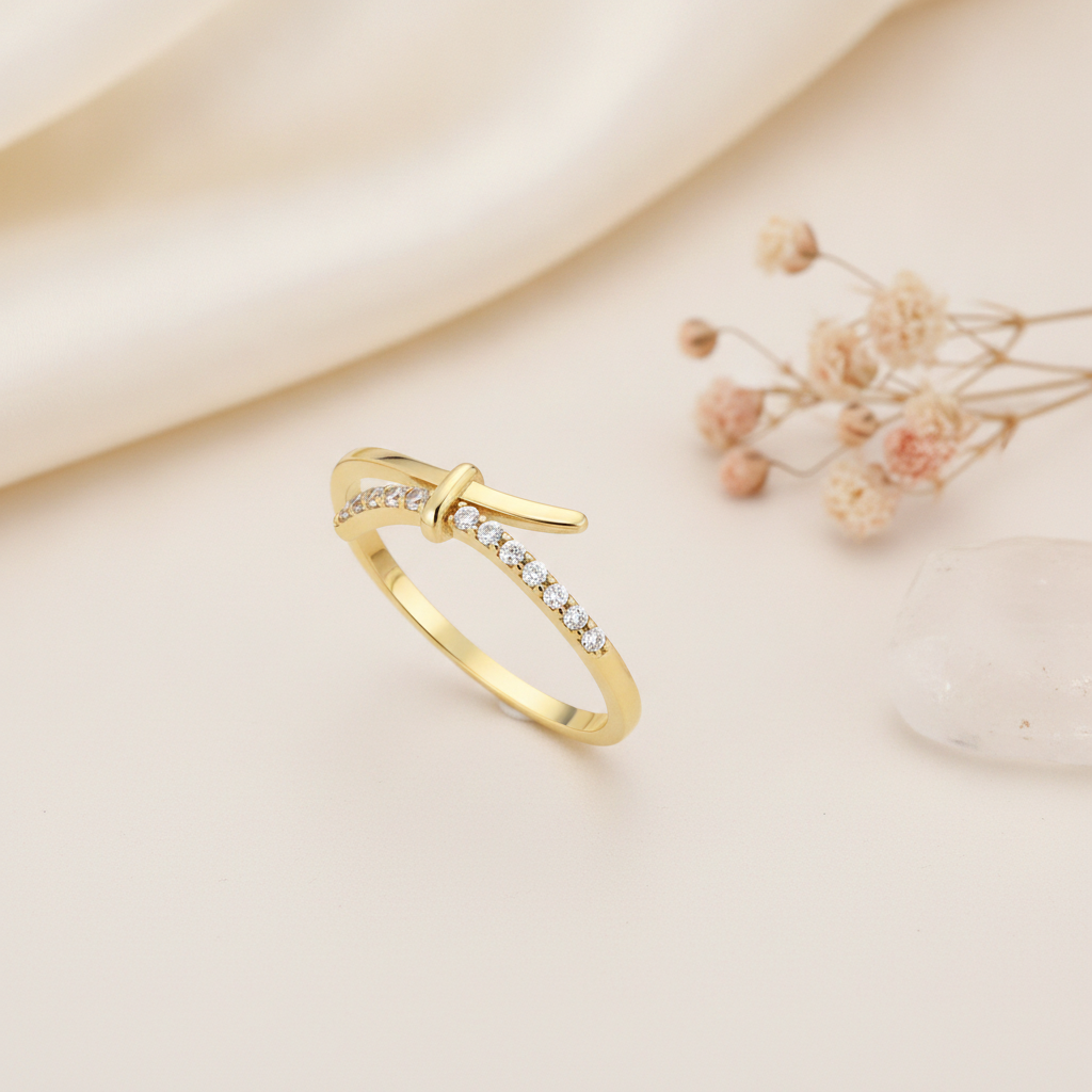 gold crossover ring with a smooth band and a pave White CZ band joined by a central bar, styled with dried flowers on a cream background
