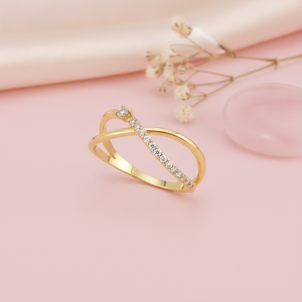 open crossover gold ring with a paved arch and a single solitaire stone, styled with dried flowers on a blush background