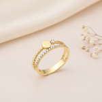 double-band gold ring with pave stones, a beaded band, and a polished gold sphere, styled with dried flowers on a blush background
