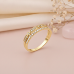 double-row gold ring with geometric stone frames and a pave band, styled with dried flowers on a blush background