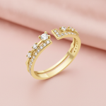 open gold ring with an elevated stone and a geometric pave crown, styled with a white rose on a blush background