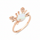 rose gold crab ring with an iridescent white stone and clear accents on white background