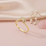 gold ring with a crescent crown of White CZ stones, styled with dried flowers on a blush background