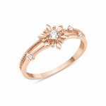 rose gold ring with a sunburst motif, central clear stone, and beaded band on white background