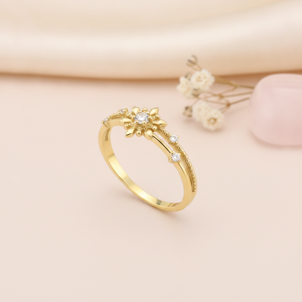 gold ring with a sunburst motif, central clear stone, and beaded band, styled with baby's breath on a blush background