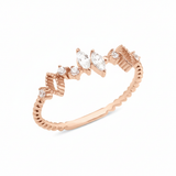 rose gold ring with marquise-cut and round stones on a textured geometric band on white background