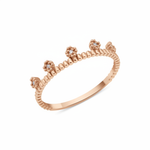 rose gold ring with floral crests set with clear stones on a beaded band on white background