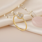 gold ring with a circular disc set with clustered White CZ stones, styled with baby's breath on a cream background