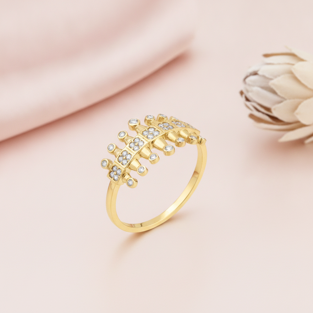 gold ring with a central row of pave-set squares flanked by textured gold pillars, on pink fabric with a dried flower
