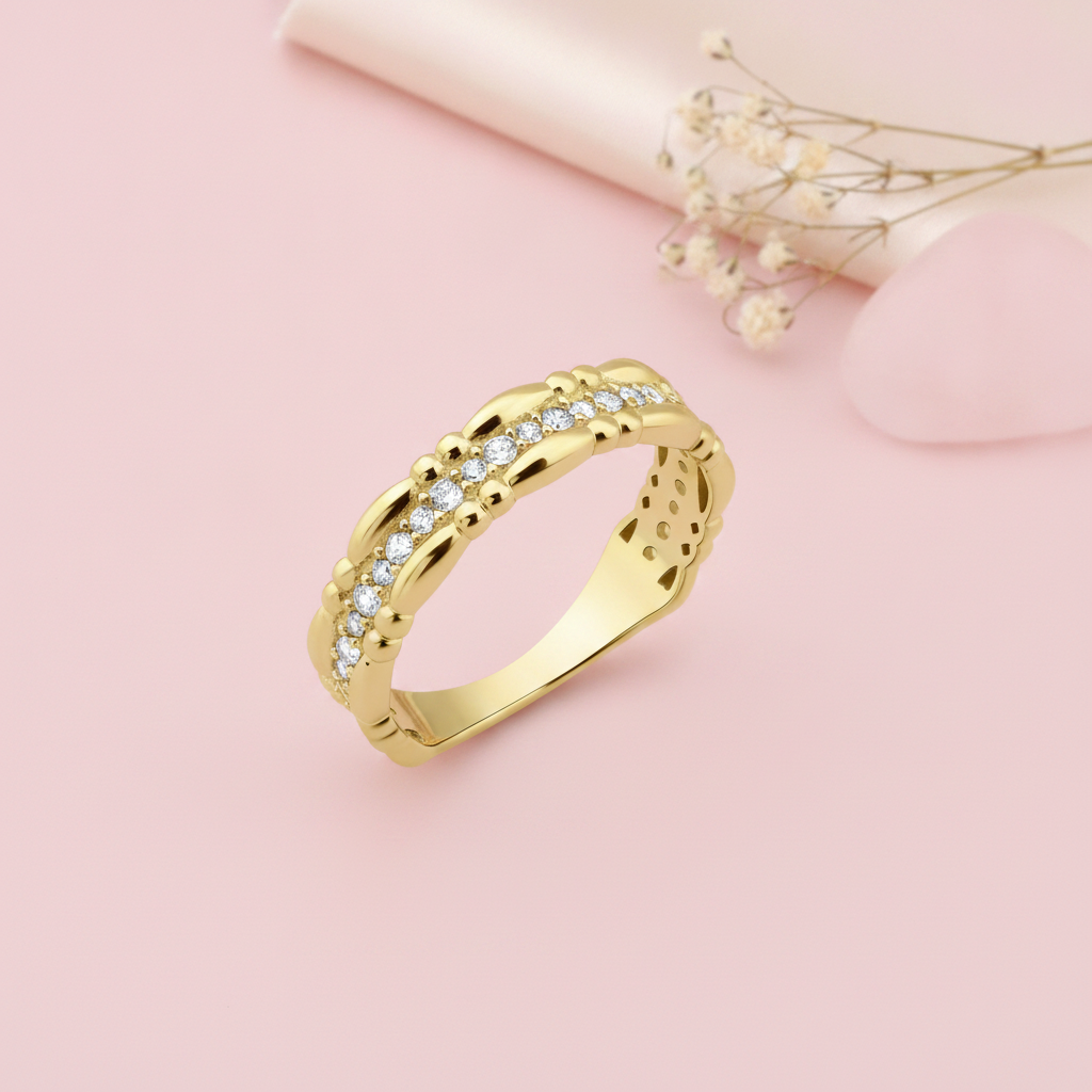 gold ring with undulating wave edges and a row of clear stones, on pink fabric with dried roses and a rose quartz stone