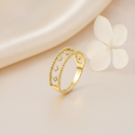 openwork gold ring with double beaded borders and kite-shaped stone settings, on cream fabric with a white flower