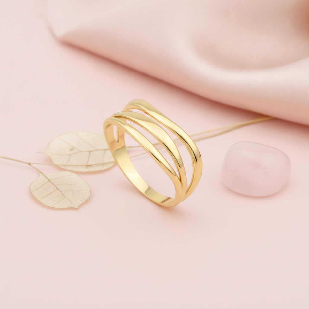 gold ring with three smooth sweeping bands and open space between, on cream fabric with a rose and dried leaves