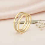wide gold ring with sweeping beaded and pave rows, on pink fabric with dried flowers and a pink stone