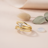 gold ring with a floral cluster and a beaded edge row of clear stones, on cream fabric with dried flowers