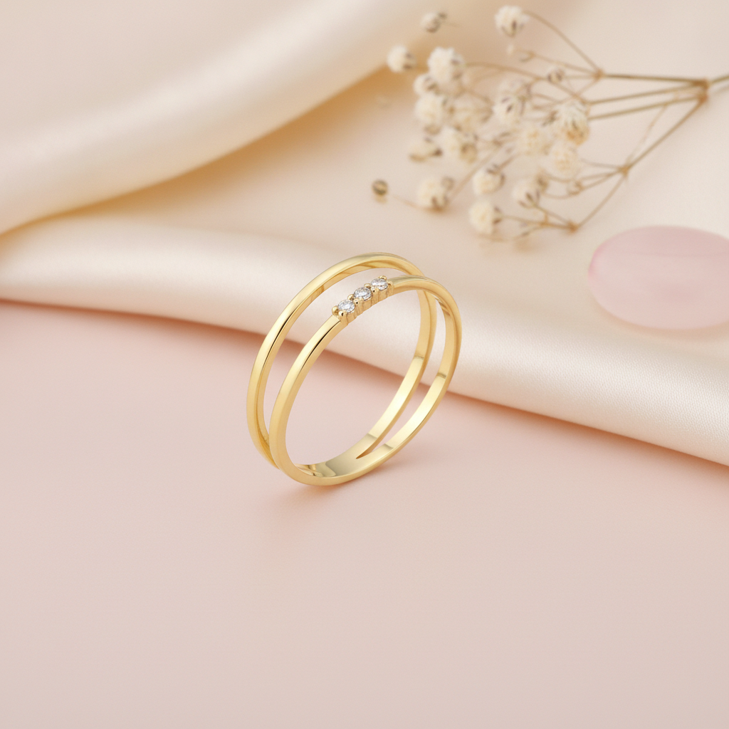 dual-band gold ring with three round clear stones in a row, on blush fabric with dried flowers
