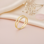 dual-band gold ring with three round clear stones in a row, on blush fabric with dried flowers