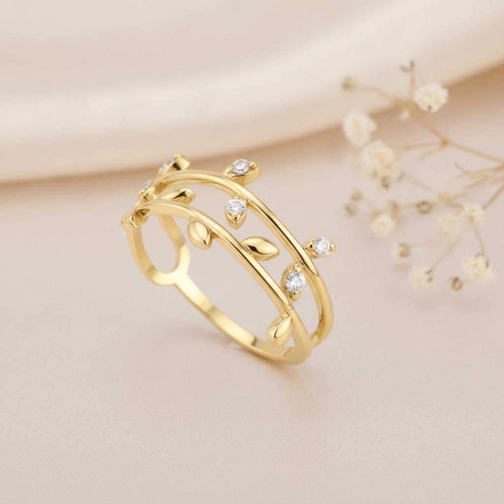 gold vine-inspired ring with sculpted leaves and clear stones, on cream fabric with dried flowers
