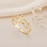 gold vine-inspired ring with sculpted leaves and clear stones, on cream fabric with dried flowers