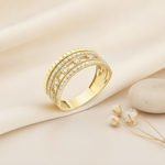 wide gold statement ring with a ribbed border and rows of pave clear stones, on cream fabric with a dried flower