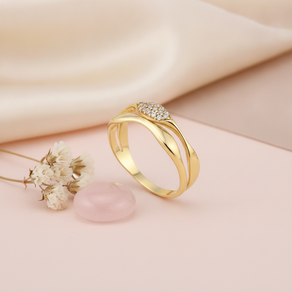 split-band gold ring with a smooth curve and a marquise cluster of clear stones, on pink fabric with a peony flower