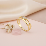 split-band gold ring with a smooth curve and a marquise cluster of clear stones, on pink fabric with a peony flower