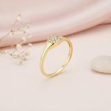 gold signet ring with a circular pave stone crest, on cream fabric with a dried flower