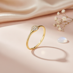 sleek gold ring with a central domed cluster of pave clear stones, on cream fabric with a dried flower