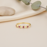 wavy gold ring with five pink stones on cream fabric with a smooth pebble and eucalyptus sprig