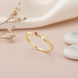 gold ring with three organic swells set with clear and magenta stones on pink silk with dried flowers and a dried artichoke pod