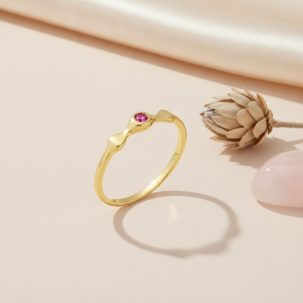 sculptural gold ring with a pink gemstone droplet on pink silk with a dried thistle pod and rose quartz stone