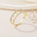 openwork gold ring with two pave rows and gold sphere accents on cream fabric with dried flowers