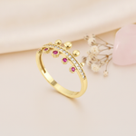 crown-shaped gold ring with pink gems, clear pave stones, and gold beads on pink silk with a rose quartz stone and dried flowers