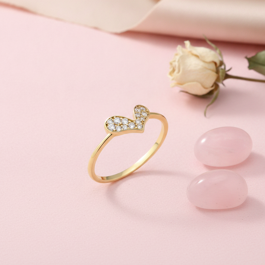 gold ring with a tilted pave heart, styled with a dried rose and pink stones on a blush background