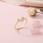 gold ring with a tilted pave heart, styled with a dried rose and pink stones on a blush background