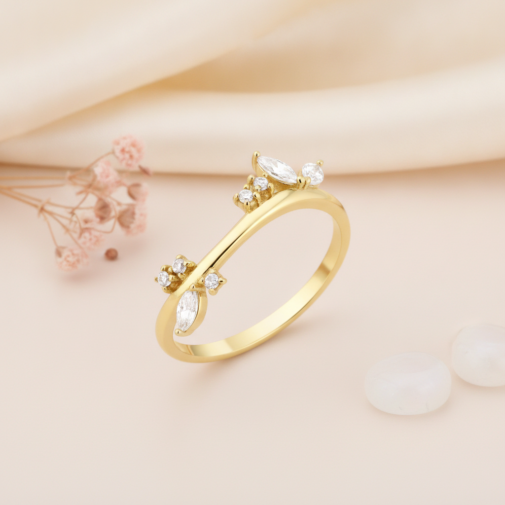 gold ring with a curved silhouette set with marquise and round clear stone clusters on cream silk with blush flowers