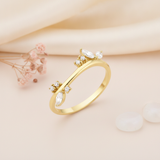 gold ring with a curved silhouette set with marquise and round clear stone clusters on cream silk with blush flowers
