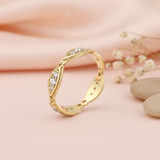 undulating gold ring with milgrain-beaded marquise stations and clear stones on cream silk with dried flowers