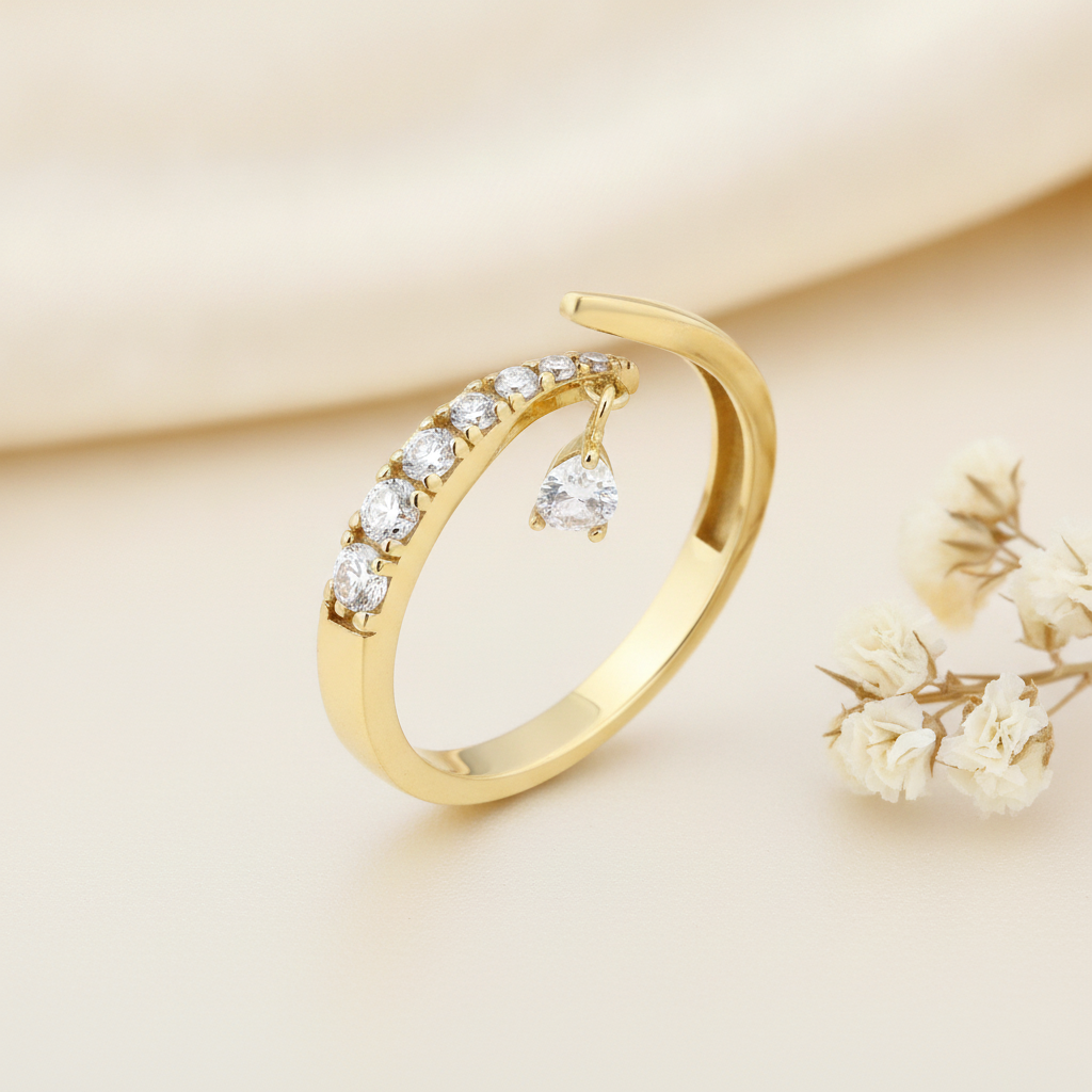 open gold bypass ring with an arch of clear pave stones and a dangling teardrop charm on cream silk with dried flowers