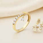 open gold bypass ring with an arch of clear pave stones and a dangling teardrop charm on cream silk with dried flowers