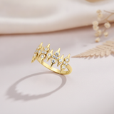 sculpted gold statement ring with pointed crests and clear round stones on blush pink fabric with a dried fern leaf