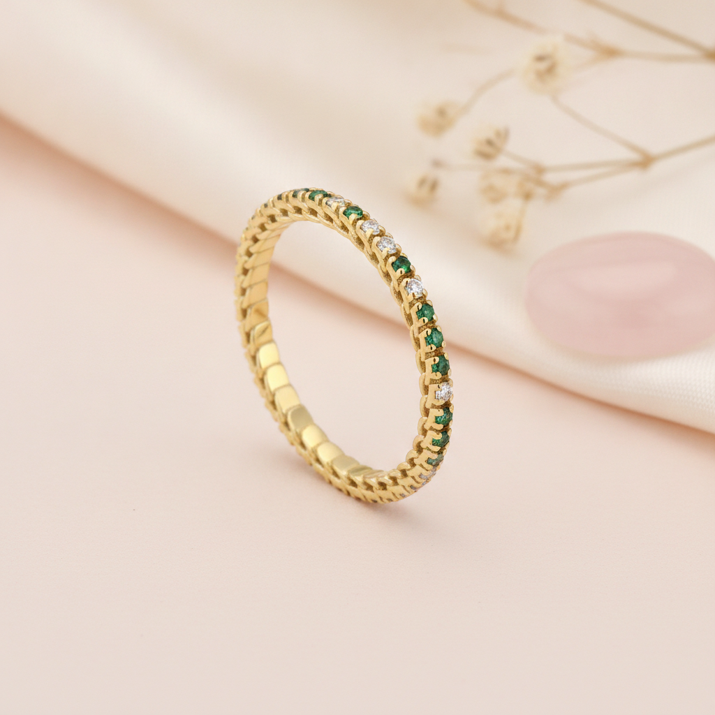 gold eternity-style ring with a row of stones transitioning from green to clear on blush silk with dried flowers and a rose quartz stone
