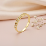 textured gold ring with a row of clear pave stones along a hammered-look band on blush silk with dried flowers and a pebble