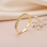 textured gold ring with a row of clear pave stones along a hammered-look band on blush silk with dried flowers and a pebble