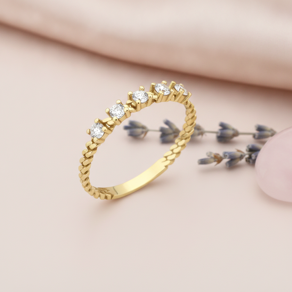 gold ring with five prong-set clear stones on a twisted rope textured band on blush silk with a lavender sprig and rose quartz
