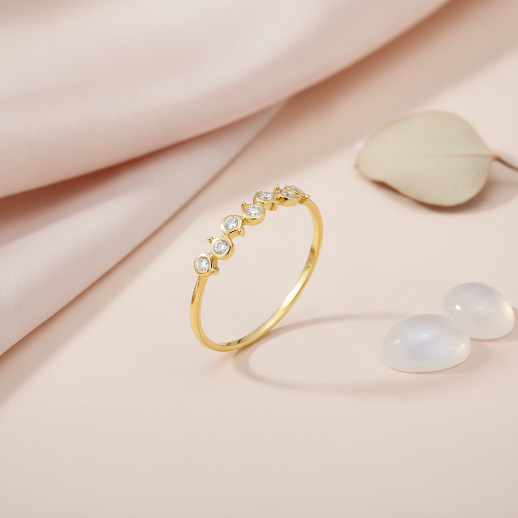 gold ring with seven round bezel-set clear stones along an undulating arc on blush silk with a lavender sprig and rose quartz