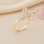 gold ring with four asymmetrical bezel-set clear stones on a polished band on blush silk with dried flowers and rose quartz