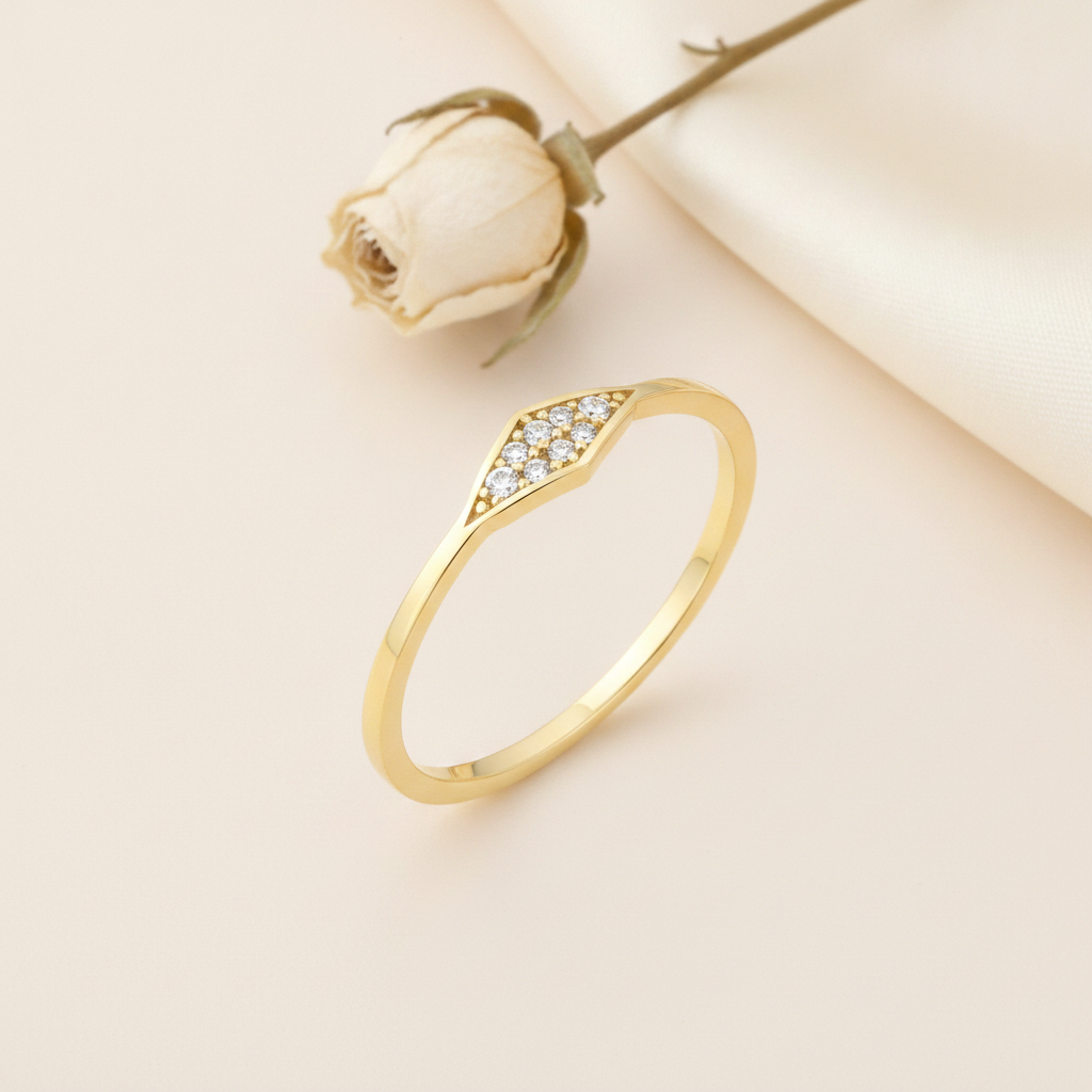 gold ring with an elongated kite-shaped pave crest on cream silk with a dried rose